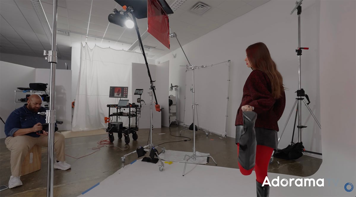 Beauty lighting setup with Rosco R26 Light Red gel positioned in front of a bare bulb flash, casting vibrant red light on a model.