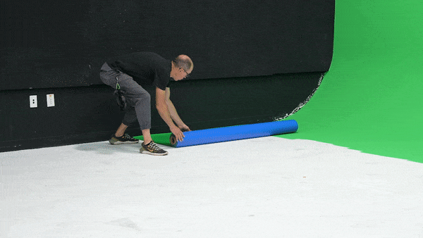 Installing a chroma key green floor inside the virtual production studio, then taping it down with chroma key green gaffer tape..