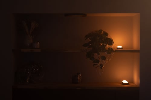 Two DMG DASH lights “Firelight" mode are placed on a bookshelf to create an eery, warm light in the background of the scene.