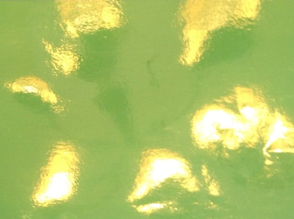 Glossy reflections creating hot spots on a green surface, interfering with keying