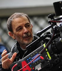 Portrait of the cinematographer Jose Luis Alcaine holding the camera.