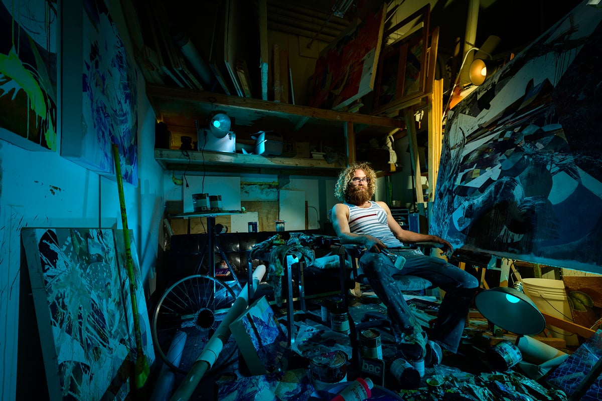 Portrait of an artists in his studio illuminated with saturated blue color.