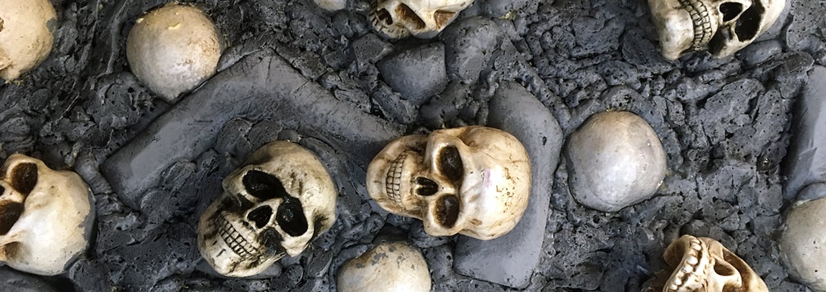 White skulls are embedded into a grey foam wall to create durable Halloween scenery.