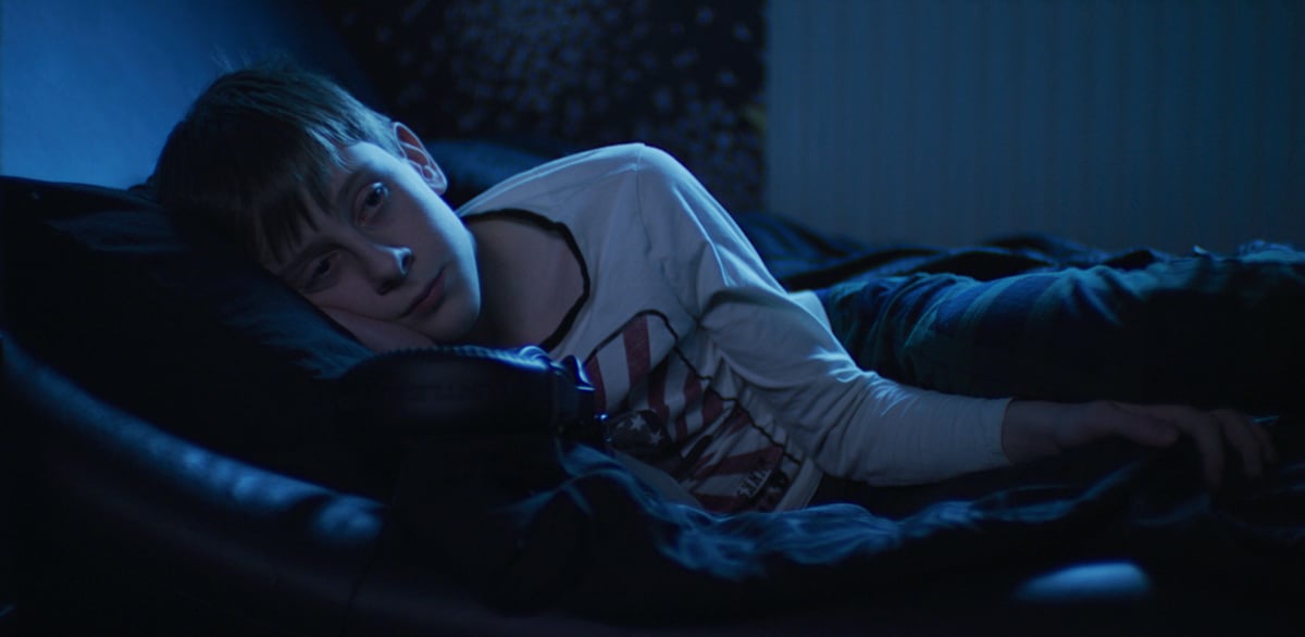 A small boy lying on a bed lit with DMG Lumière SWITCH LED lights.
