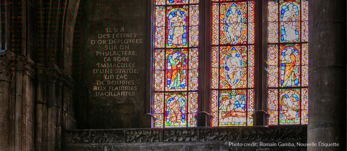 Image Spot gobo projectors create illuminated text on the wall next to a stained glass window inside the Metz Cathedral in France.