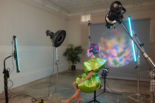 In this photography lighting setup, a Westcott Optical Spot projects a Rosco Kaleidoscope Prismatic Gobo onto the model and the background.