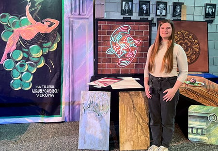 Photo of Scenic Artist Toni Conover posing with her Neon scenery project that she painted with Rosco Fluorescent Paint.